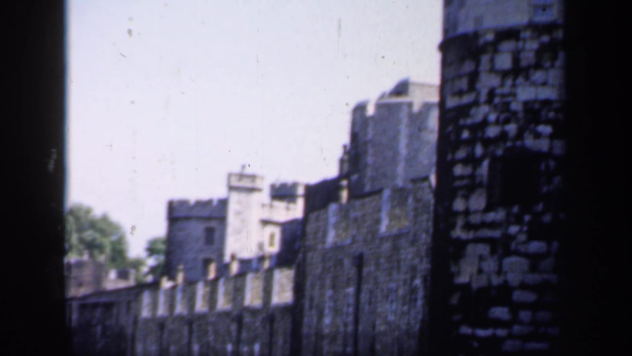 1949 8mm frame showing the Tower of London walls and battlements, partly divided by a dark foreground edge during the pan.