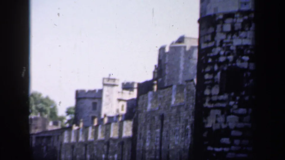 1949 8mm frame showing the Tower of London walls and battlements, partly divided by a dark foreground edge during the pan.