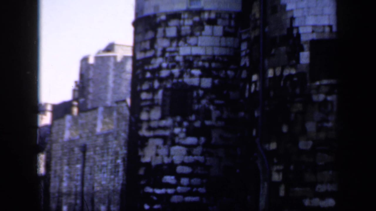 1949 8mm view of round Tower of London masonry beside adjoining stone walls, softened by motion and film grain.
