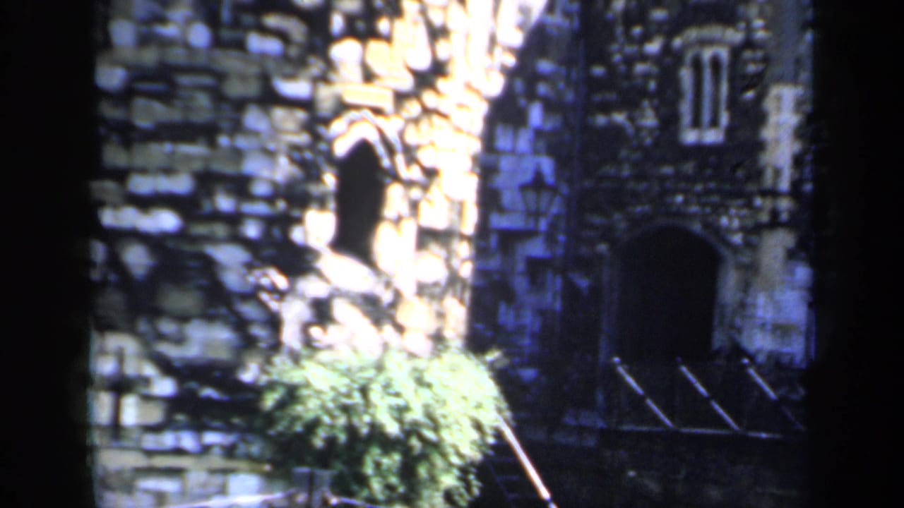 Old stone building with arched openings beside a sunlit historic street.