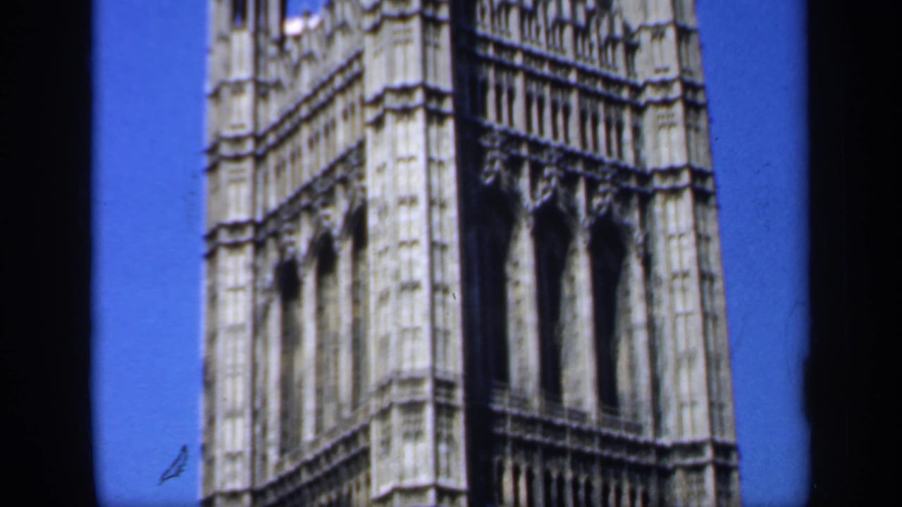 1949 England frame showing a tall Gothic facade, possibly part of the Palace of Westminster, with arched openings and pale stonework.