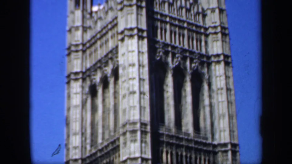 1949 England frame showing a tall Gothic facade, possibly part of the Palace of Westminster, with arched openings and pale stonework.