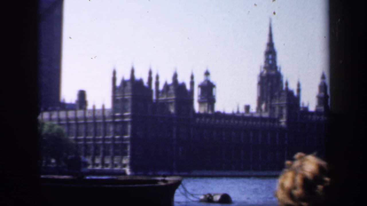 1949 home-movie frame of Westminster and Big Ben across the Thames, with a passenger's head at lower right.
