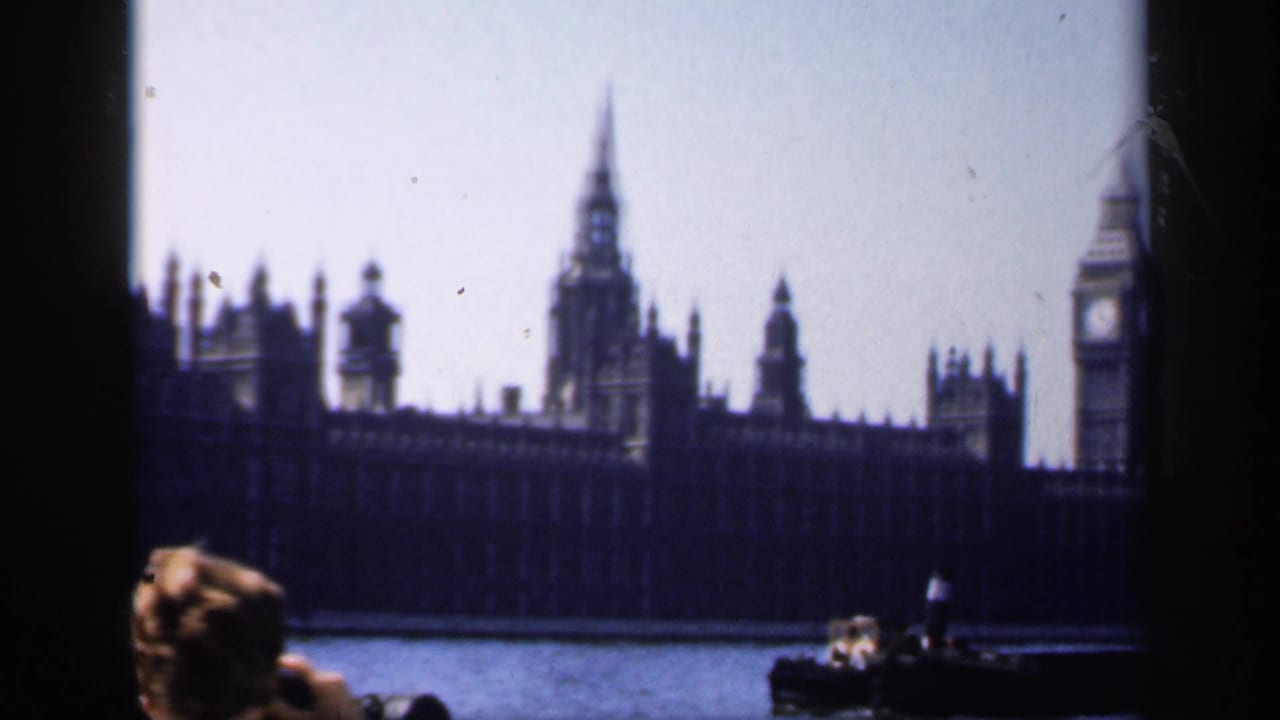 1949 8mm travel view of Big Ben and the Palace of Westminster from the Thames, with a passenger in the foreground.