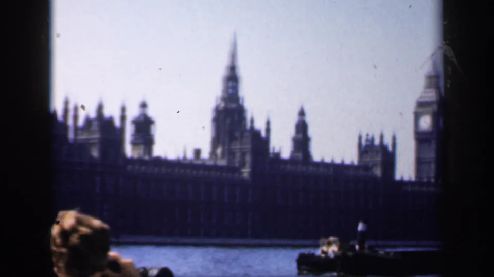 1949 8mm travel view of Big Ben and the Palace of Westminster from the Thames, with a passenger in the foreground.