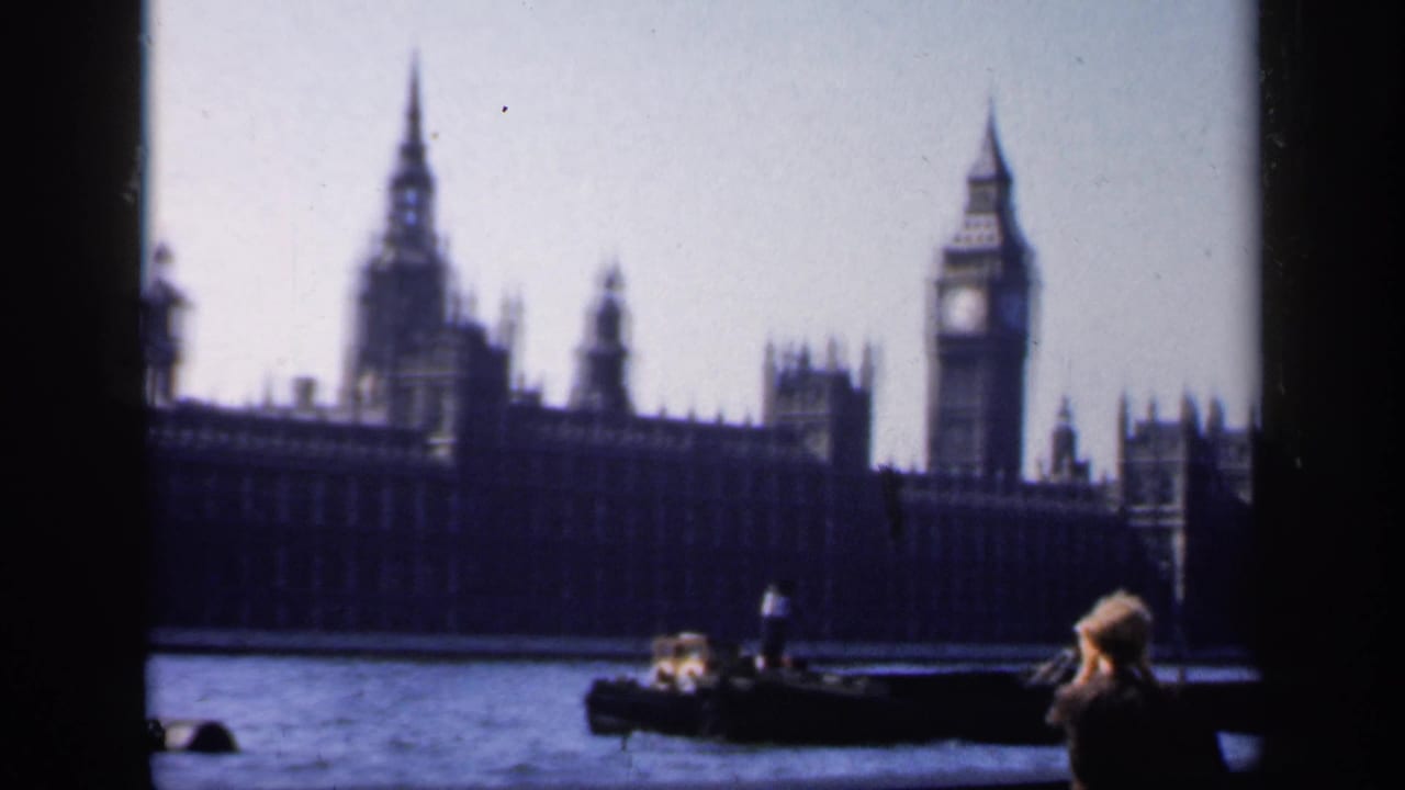 1949 8mm frame showing Big Ben, Westminster, small river boats, and a foreground figure taking a photograph.