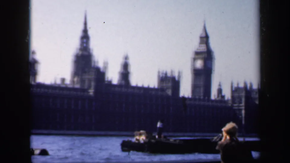 1949 8mm frame showing Big Ben, Westminster, small river boats, and a foreground figure taking a photograph.