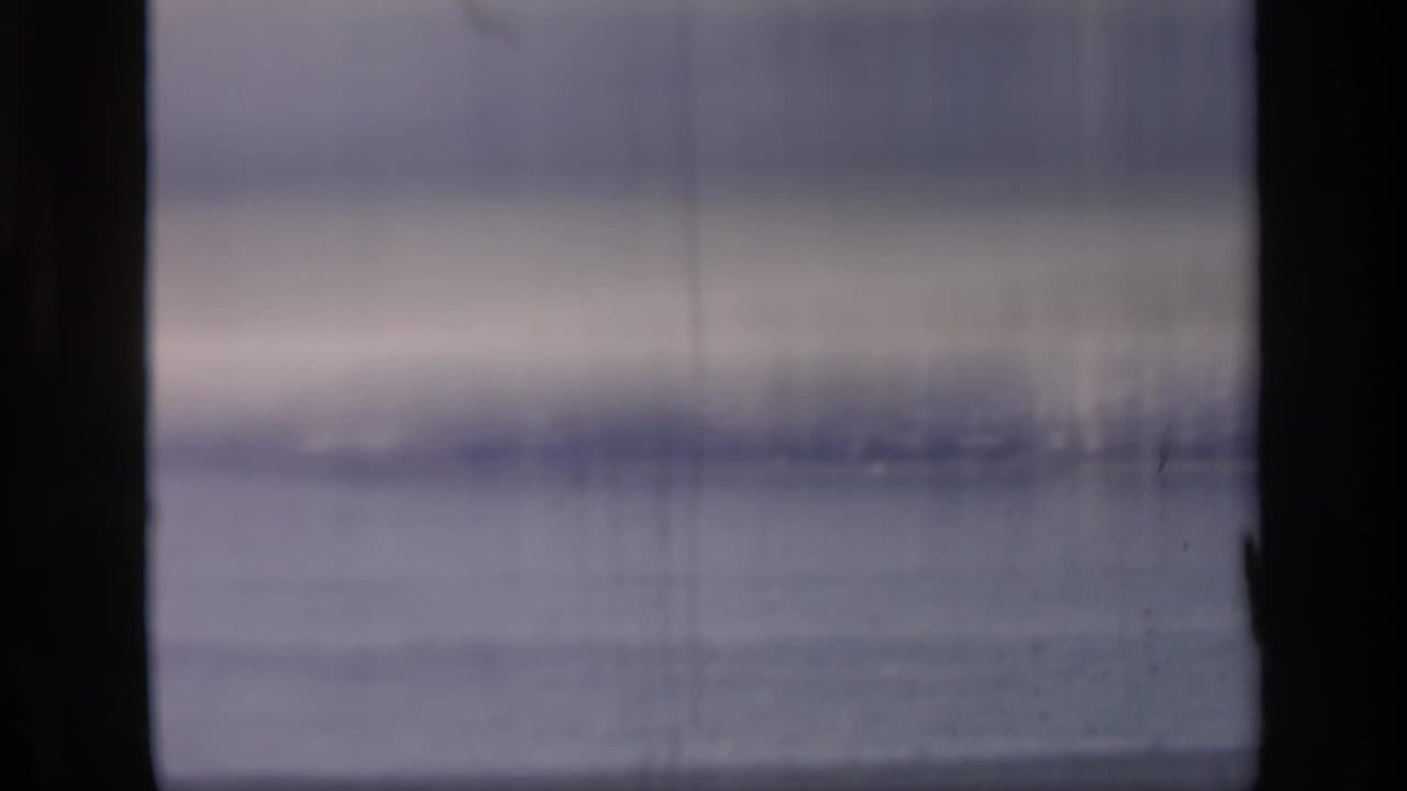 Soft 8mm frame dominated by the Thames surface, with muted color, vertical film marks, and little distinct detail.
