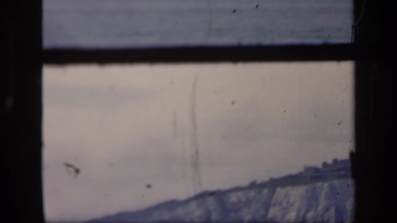 1949 London Thames view with a hazy riverside skyline, pale sky, dark frame edges, and visible 8mm film wear.
