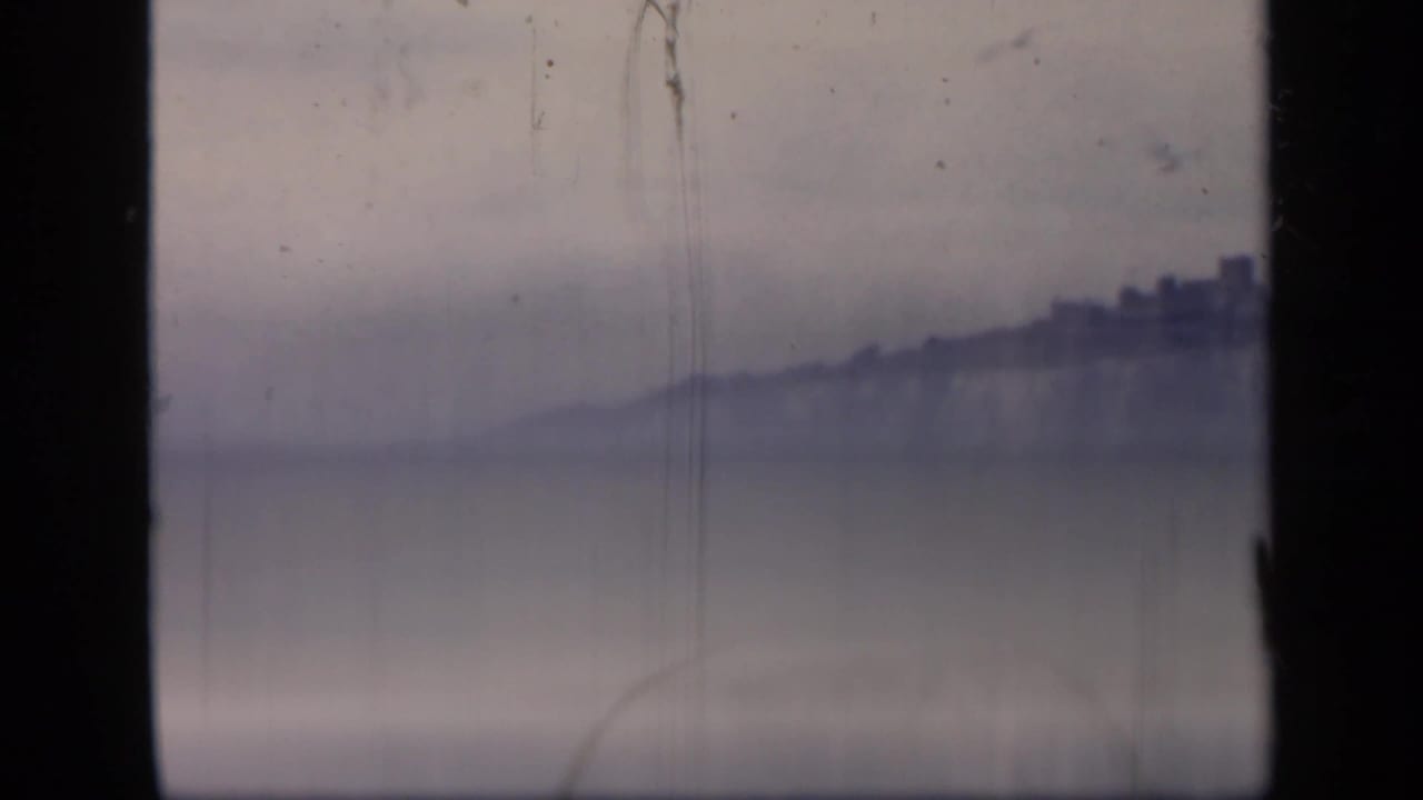 Soft distant chalk cliff and water framed by dark vertical window edges.