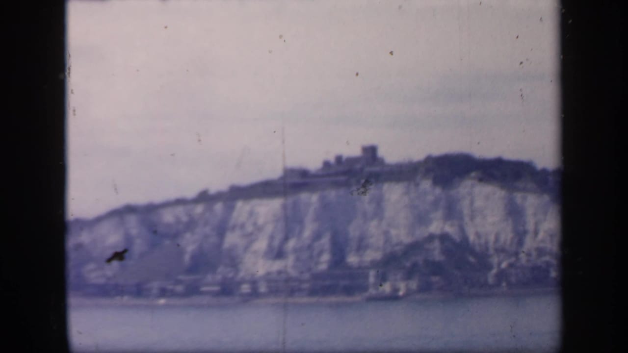 1949 England home-movie view of Dover's chalk cliffs with a castle-like structure on the ridge, filmed from across the water.