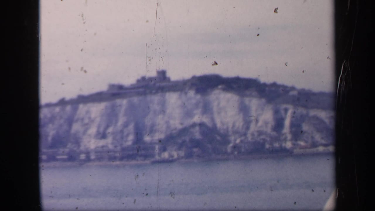 The final frame holds on Dover's chalk cliffs and castle-like ridge structure, with 8mm dust and gate marks visible.