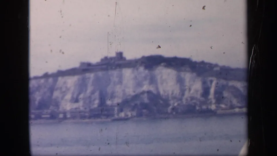 The final frame holds on Dover's chalk cliffs and castle-like ridge structure, with 8mm dust and gate marks visible.