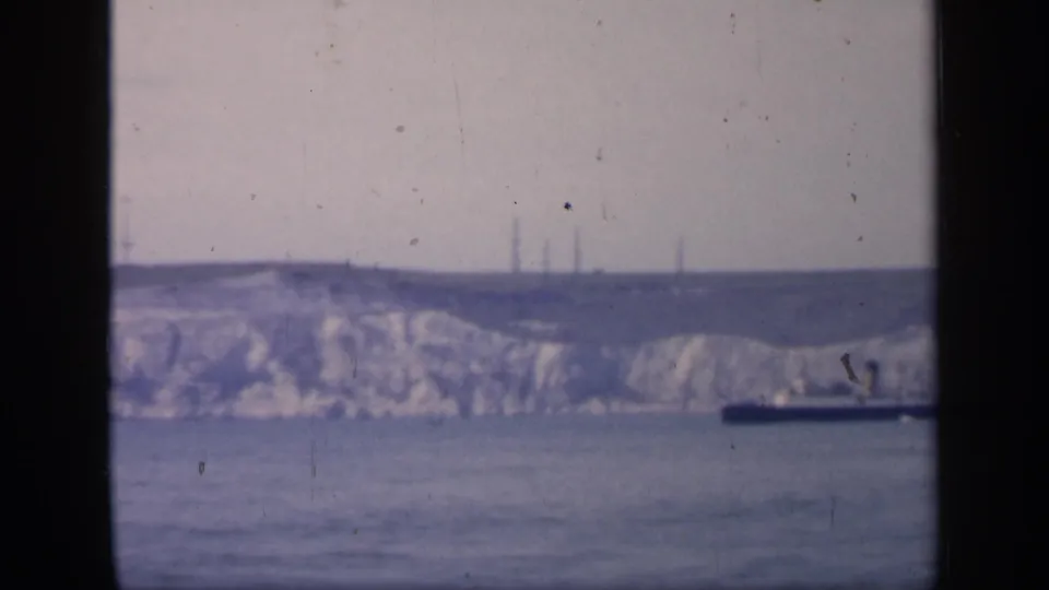 1949 England coastal view with a dark ship passing below pale chalk cliffs, framed by a central vertical window division.