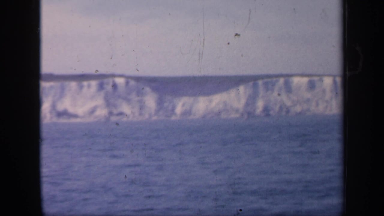 1949 England 8mm frame showing white chalk cliffs beyond the sea, partially divided by a dark sightseeing-vessel window frame.