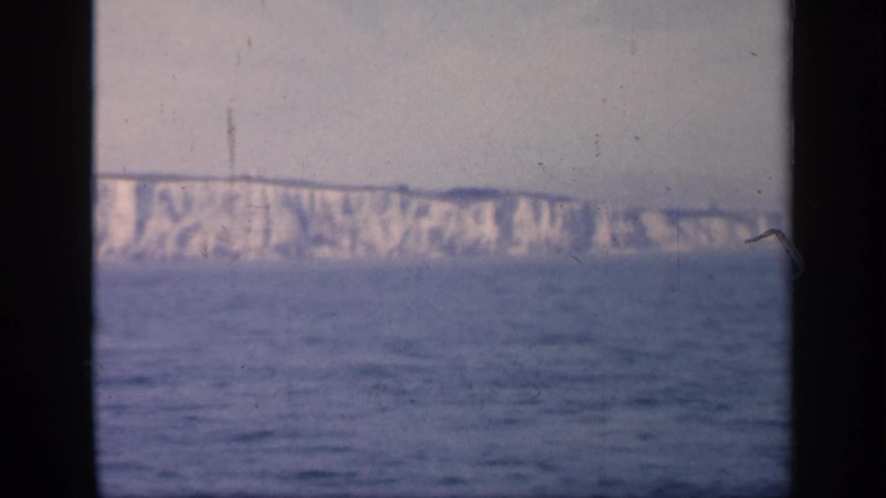 Distant Dover cliffs remain visible across the sea, with heavy dark window framing and soft 8mm color from the 1949 England footage.