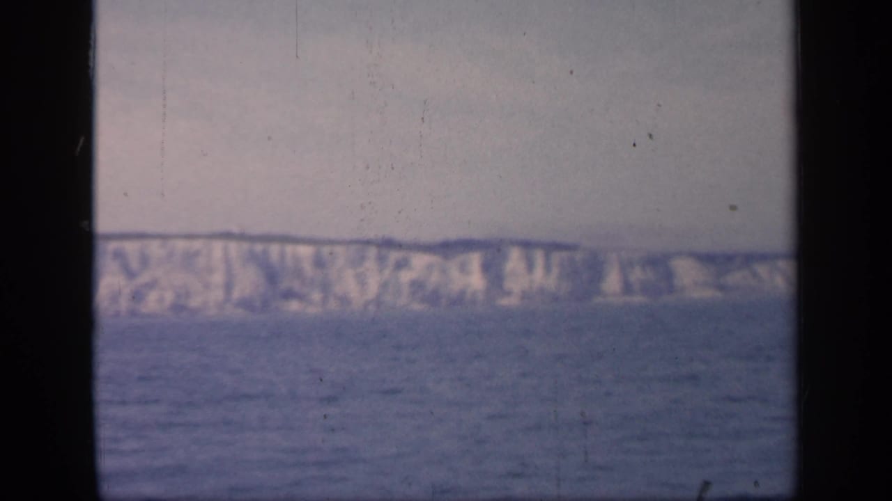 Distant white cliffs across a blue-gray sea under a hazy sky.