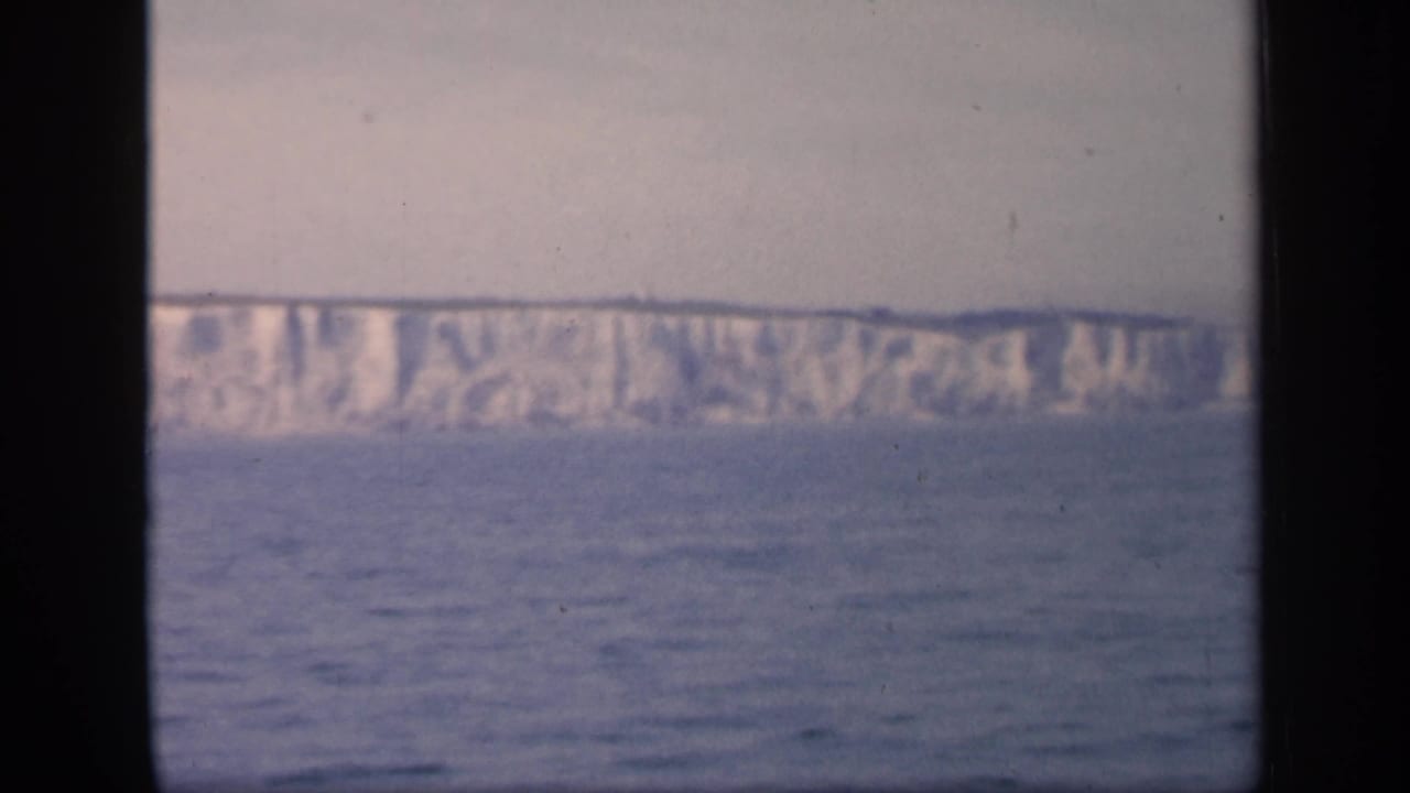 Distant chalk cliffs seen over calm blue water.