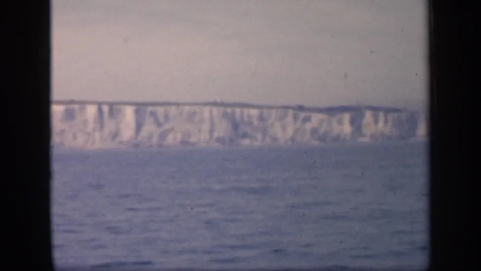Offshore view of English chalk cliffs in a soft 1949 8mm frame, with the sea filling the lower half of the scene.