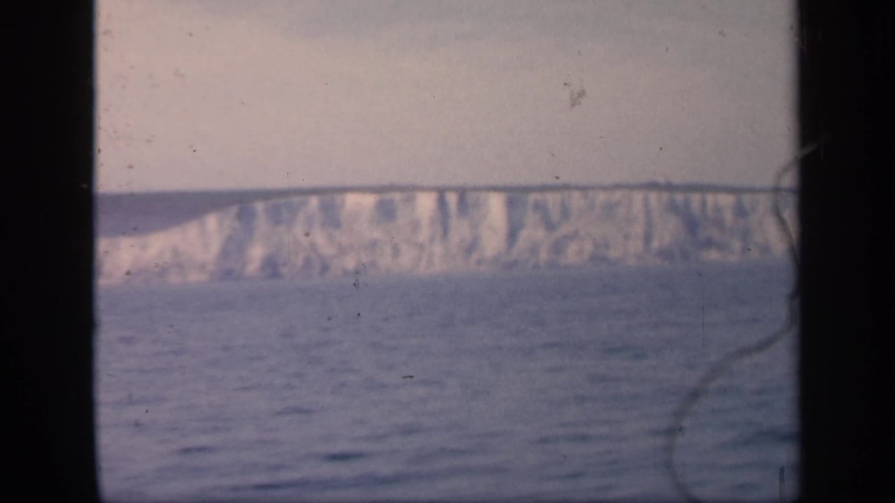 White cliffs along the English coastline appear closer in this 1949 8mm frame, with visible dust and scratches over the water and sky.