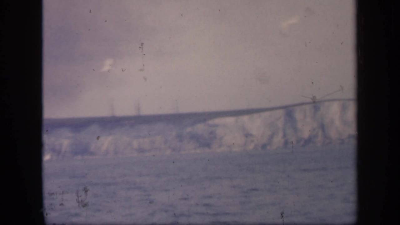 A lower, softer 8mm view shows pale coastal cliffs, open water, and dark window edges from a moving boat.