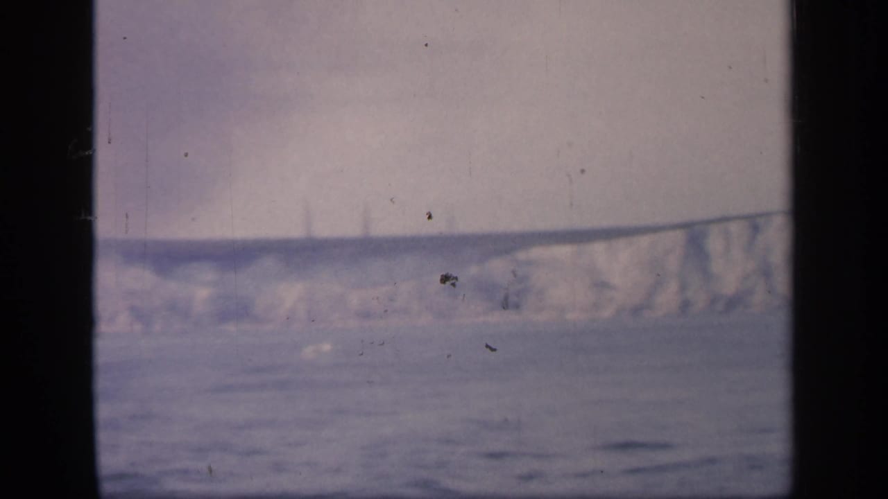 Final frame shows a partial chalk cliff line to the right, with calm water and hazy sky seen through the window.