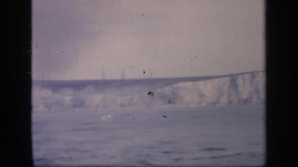 Final frame shows a partial chalk cliff line to the right, with calm water and hazy sky seen through the window.