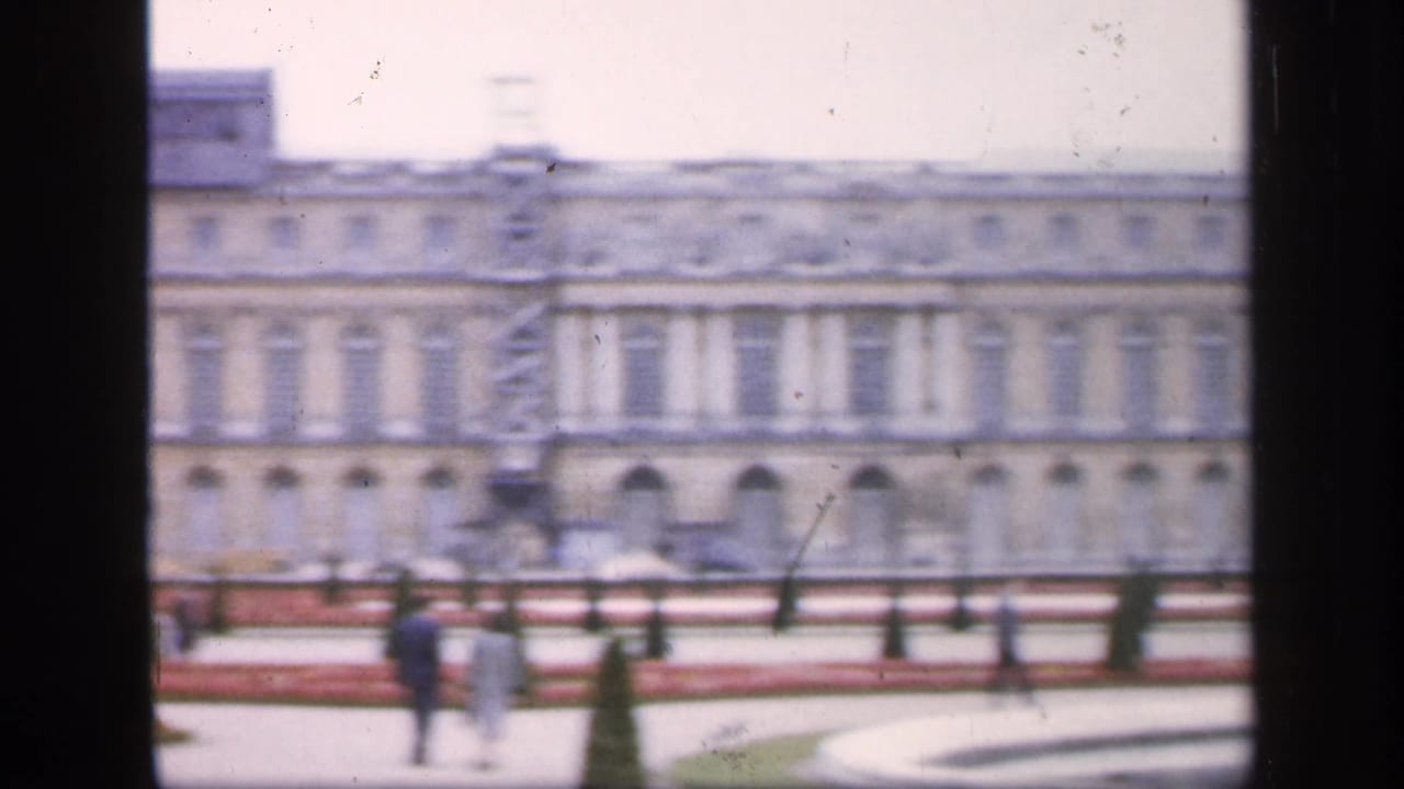 Versailles palace facade with distant visitors walking in the garden area.