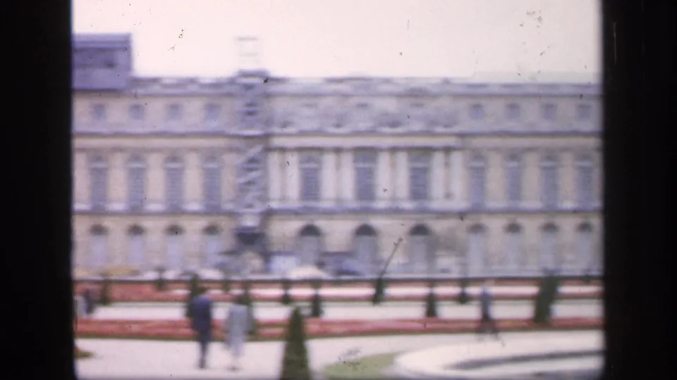 1949 Versailles garden view with the palace facade, distant visitors, formal paths, and vertical dark frame edge from the film scan.