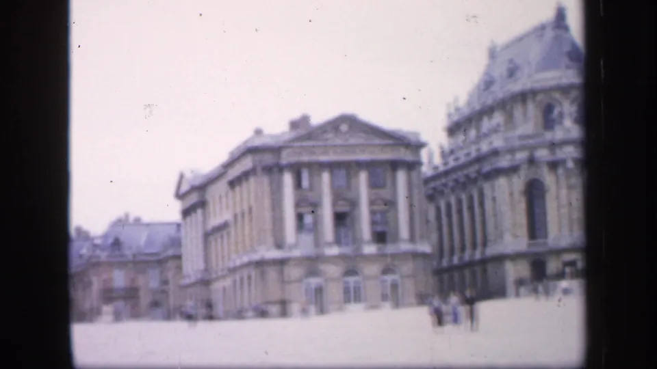 1949 8mm view in France showing a broad plaza bordered by classical buildings, including columns and a domed or rounded roofline.