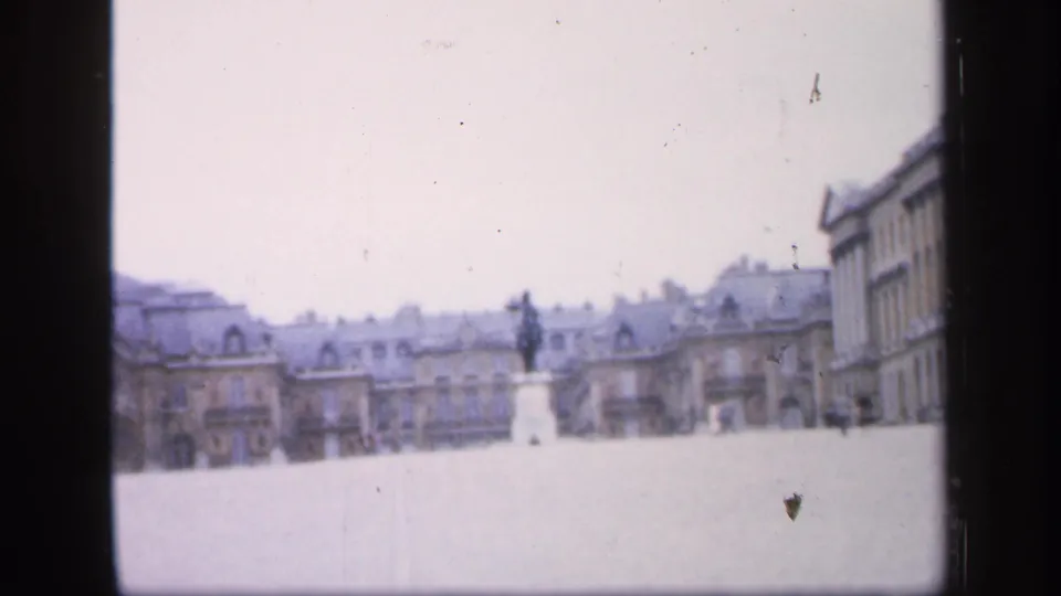 Soft 8mm frame from France in 1949 showing a statue across a broad public square with historic rooflines behind it.