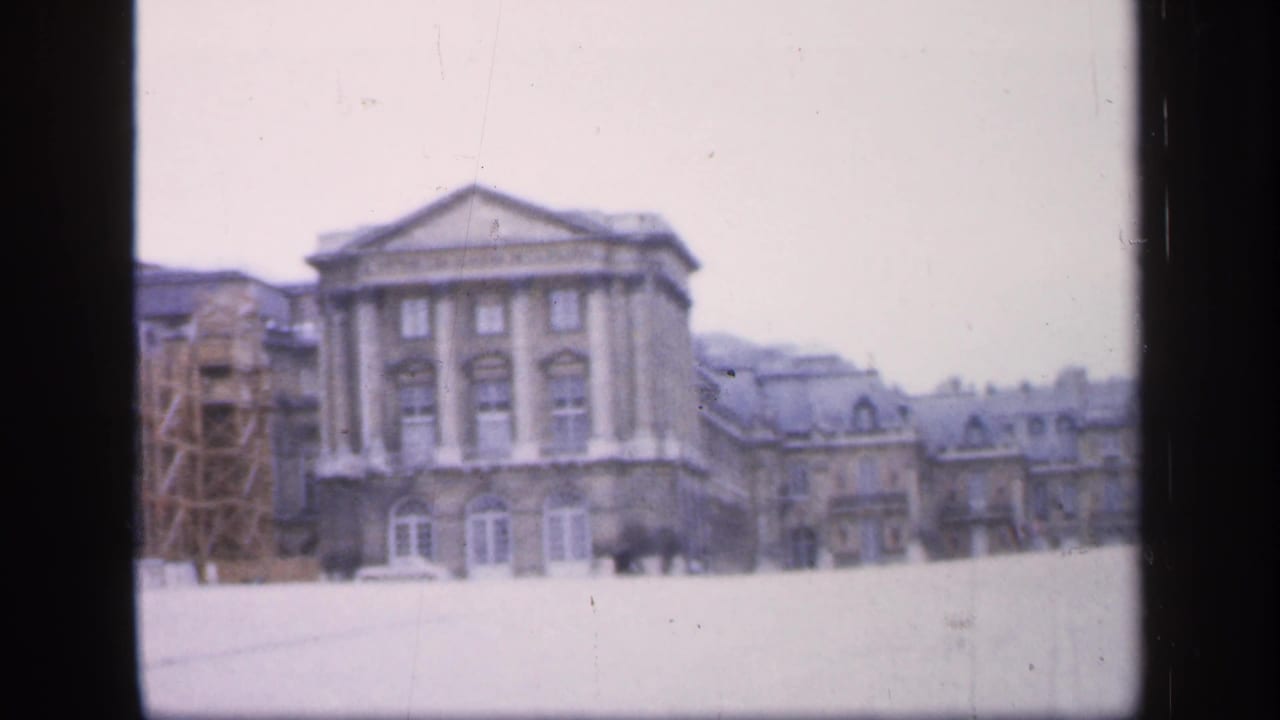 Snow-covered courtyard before a classical building with columns and a triangular pediment.
