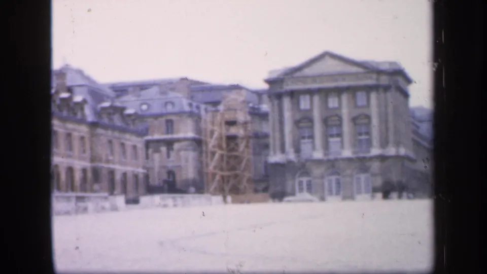 1949 France frame of a formal building complex in winter, with scaffolding visible near one wing and soft 8mm color fading.