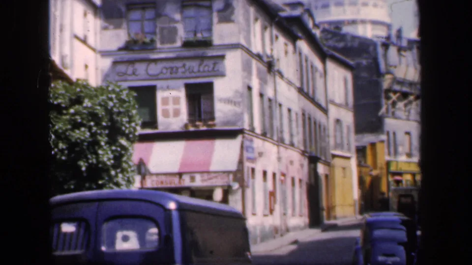 1949 France street view showing vintage cars, Le Consulat, striped awnings, and older Montmartre buildings.