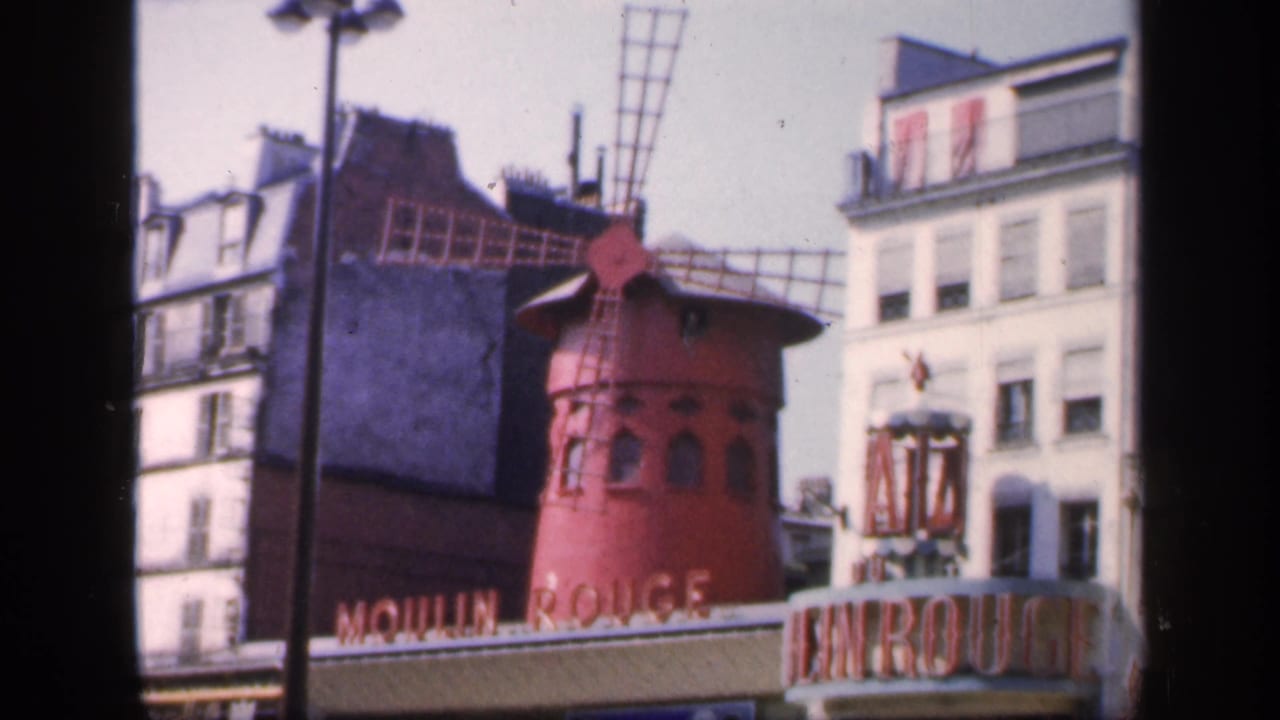 Moulin Rouge windmill and entrance seen from across a Paris street.