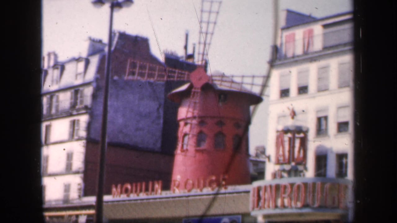 Moulin Rouge red windmill above Paris street buildings.