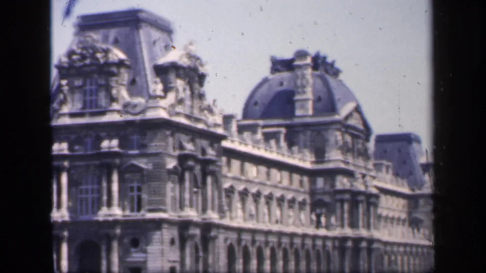 1949 Paris frame showing the Louvre Museum exterior, including ornate roofline, stone facade, and arched ground-level openings.