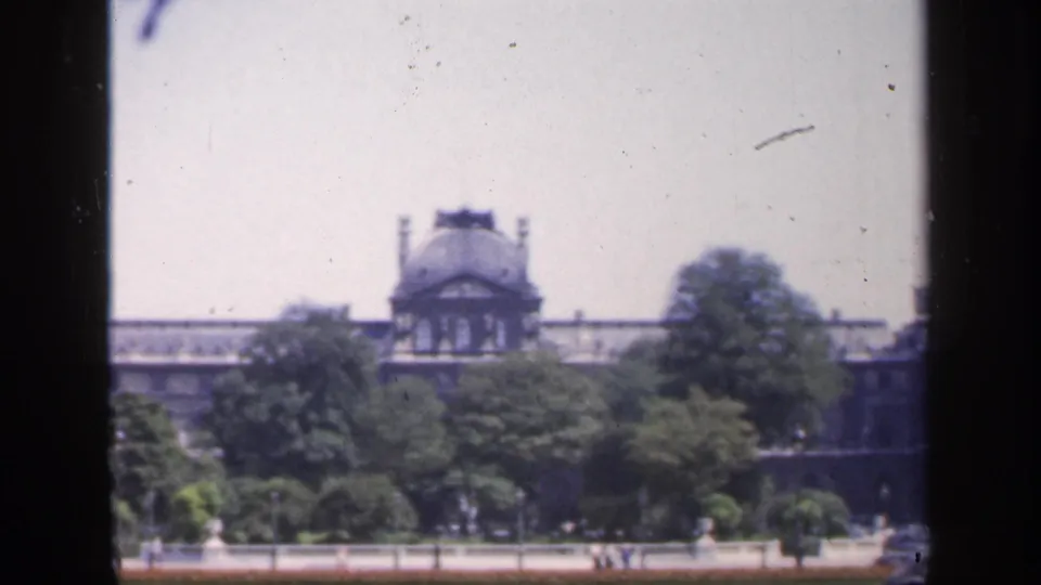 1949 France 8mm frame showing leafy grounds in front of a distant domed pavilion and long classical roofline.