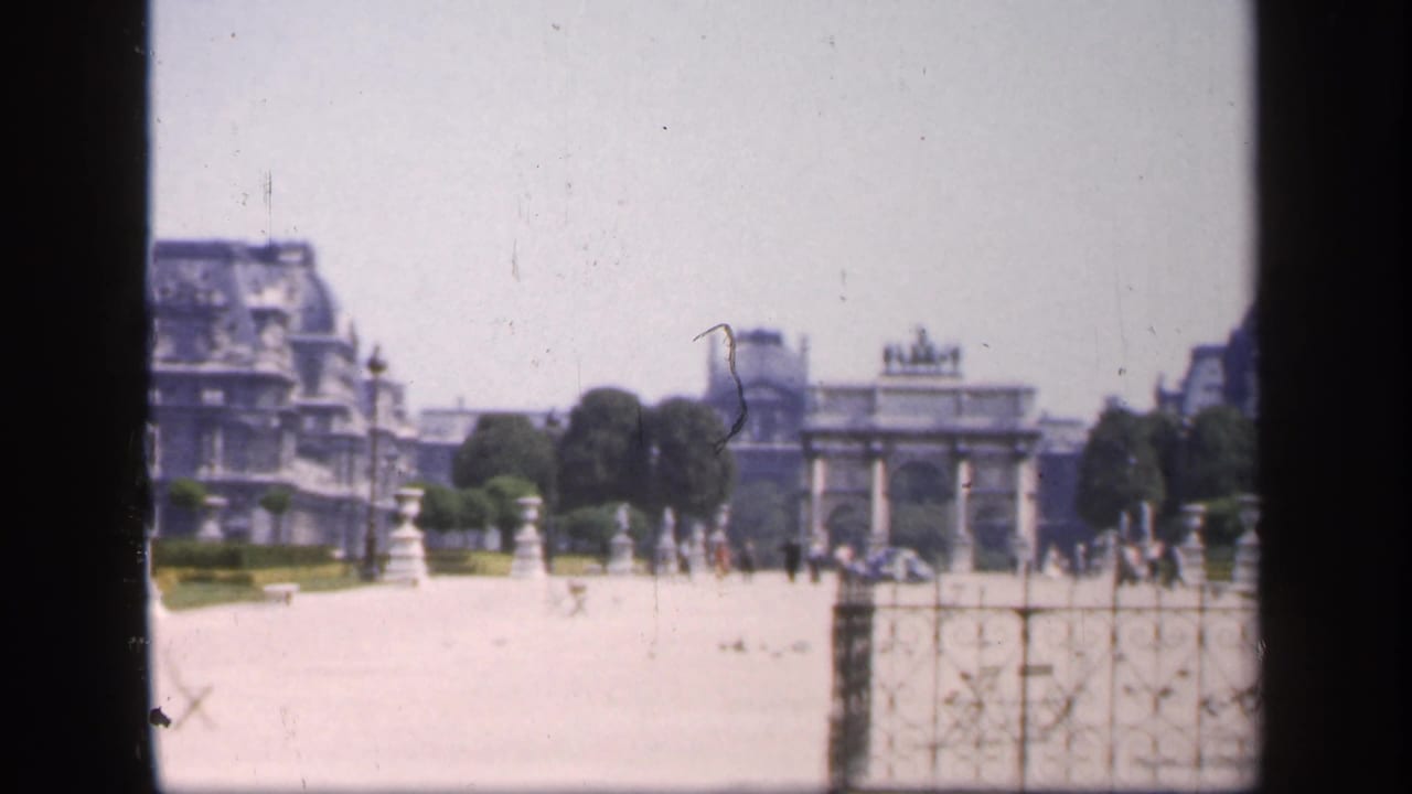 Formal garden path with a triumphal arch and distant pedestrians, partly framed by dark film edges.