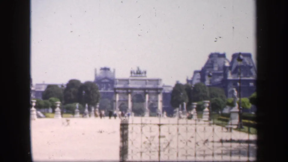 1949 France travel footage appears to show a Louvre-area courtyard or garden, with a triumphal arch centered beyond stone railings.