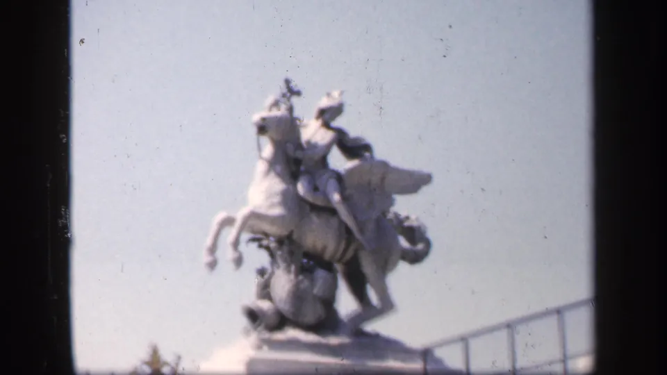 1949 France frame holding on the pale horse-and-rider monument, with soft focus, bright sky, and a low railing visible.