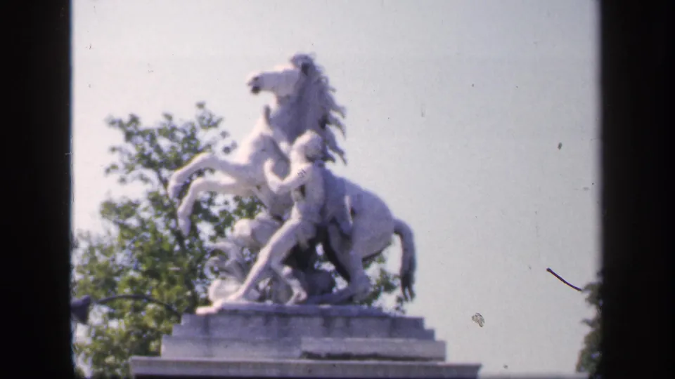 Close 1949 France view of a white horse statue on a pedestal, framed by pale sky, trees, and 8mm film borders.