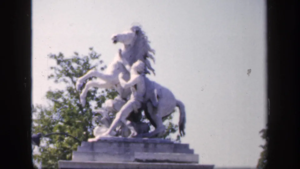 A white equestrian statue fills the frame in this supported 1949 France home-movie shot, with trees and pale sky behind.