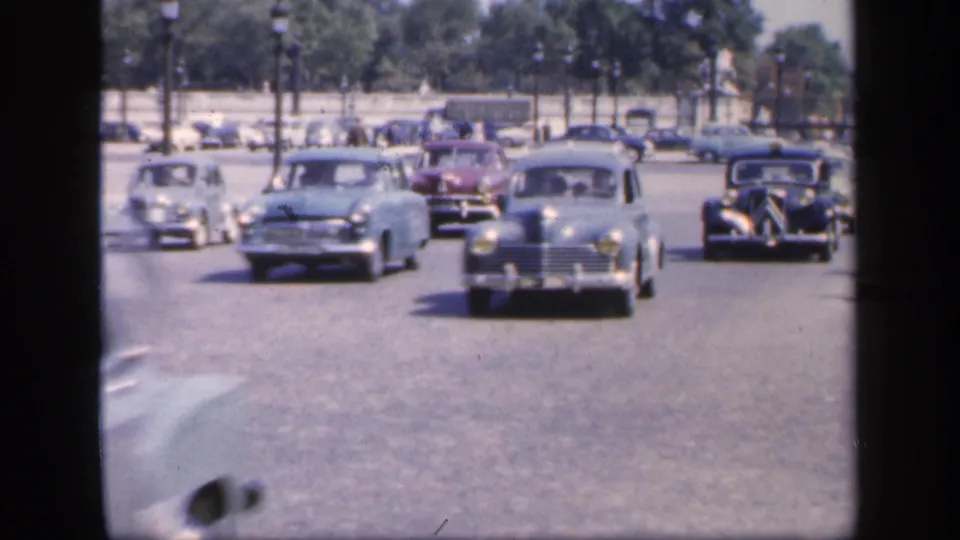 1949 France traffic scene with multiple mid-century cars moving toward the camera on a broad urban road.