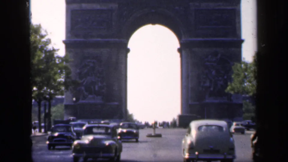 1949 Paris traffic view showing classic cars on a broad avenue with the Arc de Triomphe centered in the background.