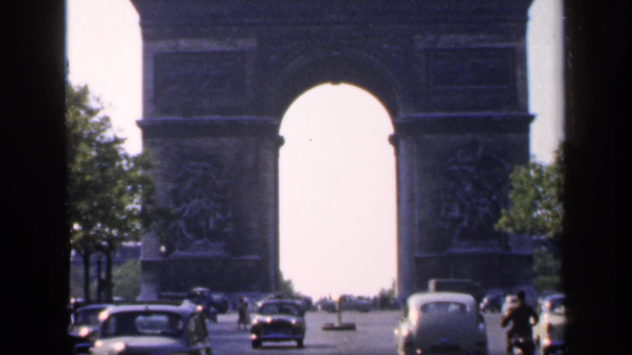 Arc de Triomphe seen through dark window bars with cars on the boulevard.