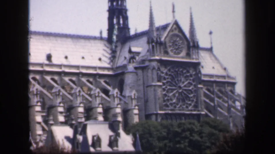 1949 France frame of Notre Dame's upper facade, rose window, roofline, buttresses, trees, and dark film border.