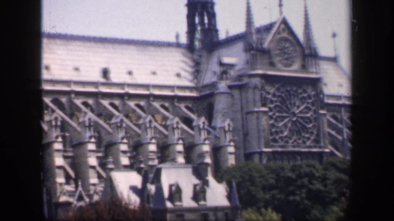 Notre-Dame exterior with rose window, flying buttresses, roofline, and trees seen through a dark film-frame border.