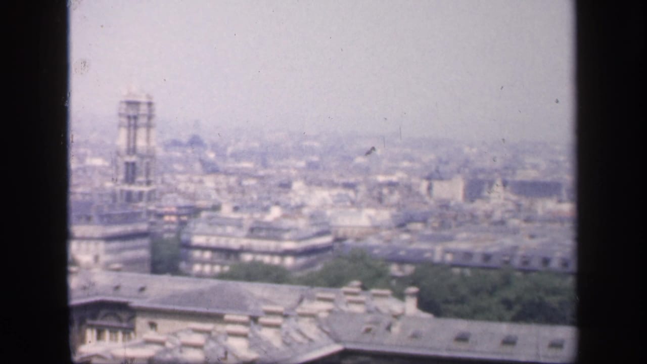 Hazy Paris rooftop panorama with a tall tower structure near the center.
