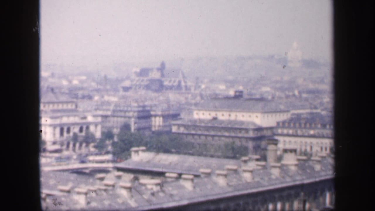 City panorama with ornate buildings, distant dome shapes, haze, and foreground bars.